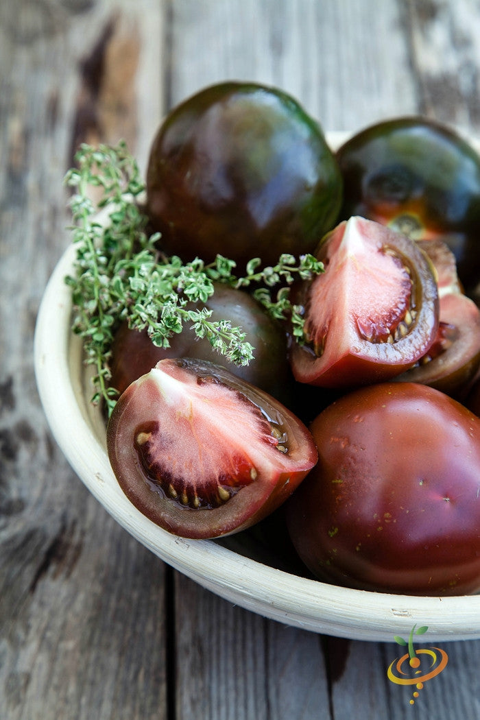 Black Krim indeterminate tomato seeds from SeedsNow, showing vibrant ripe tomatoes on the vine with dark red and green coloring.